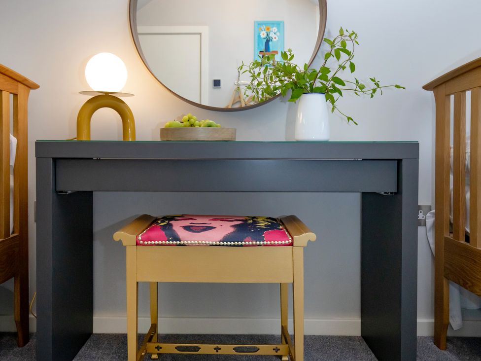 A console table with a mirror and lamp in a bedroom at Mariners Retreat, 8 Pottery Cottages in Dartmouth
