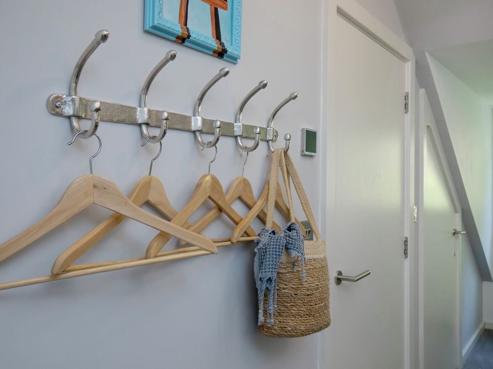 A hallway with coat hooks and a woven basket at Mariners Retreat, 8 Pottery Cottages, Dartmouth