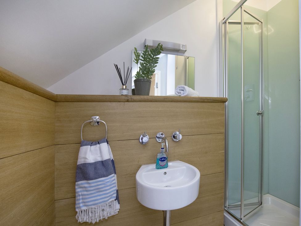 A bathroom with a sink, towel, and shower at Mariners Retreat, 8 Pottery Cottages in Dartmouth