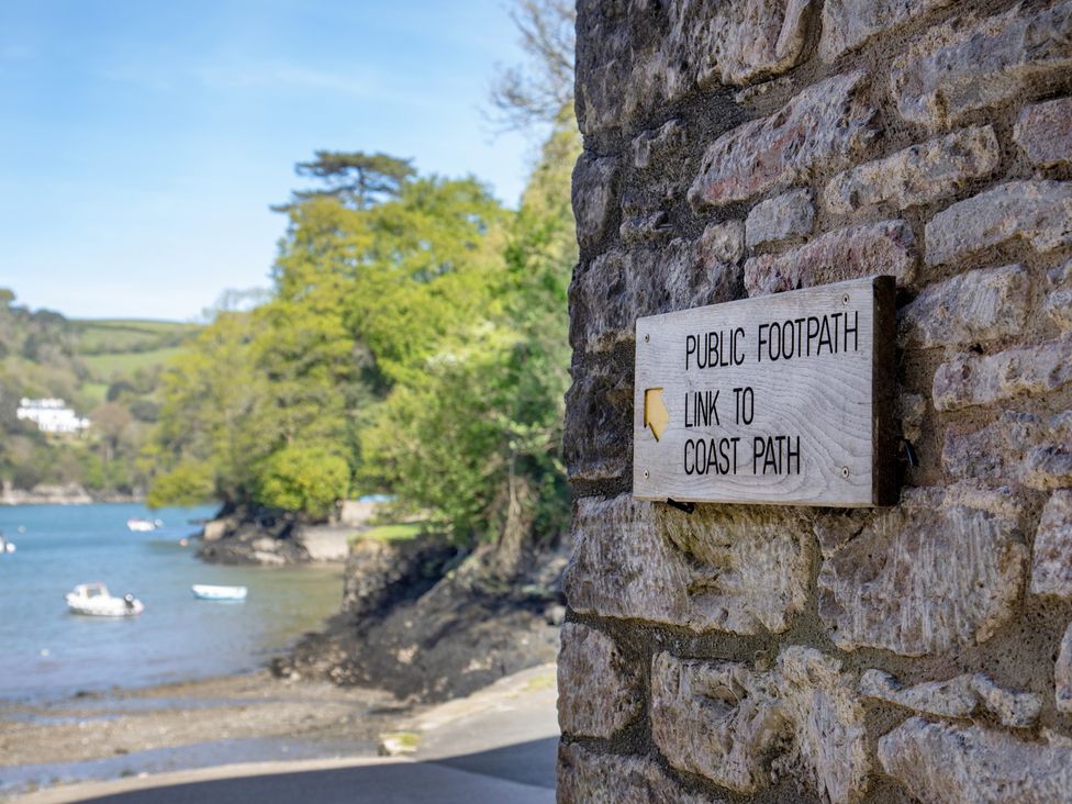 A public footpath sign leading to the coast path near a waterway in Dartmouth