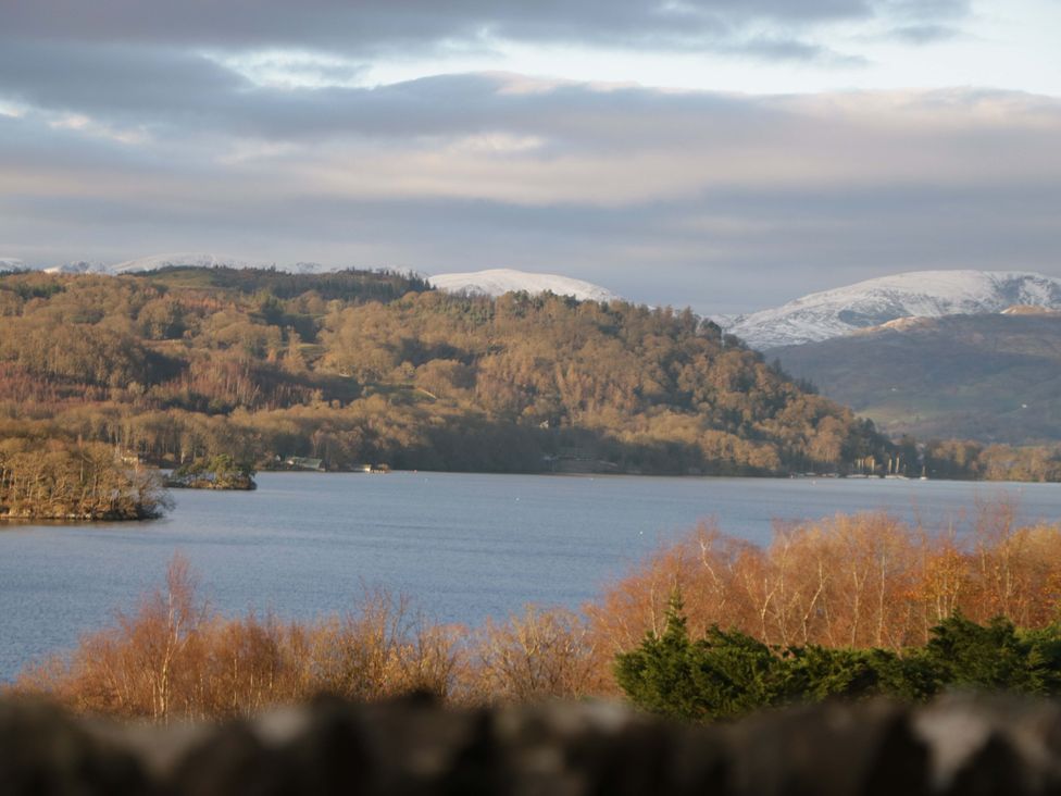 A view of a lake with surrounding mountains and trees at Marina View in Bowness-On-Windermere