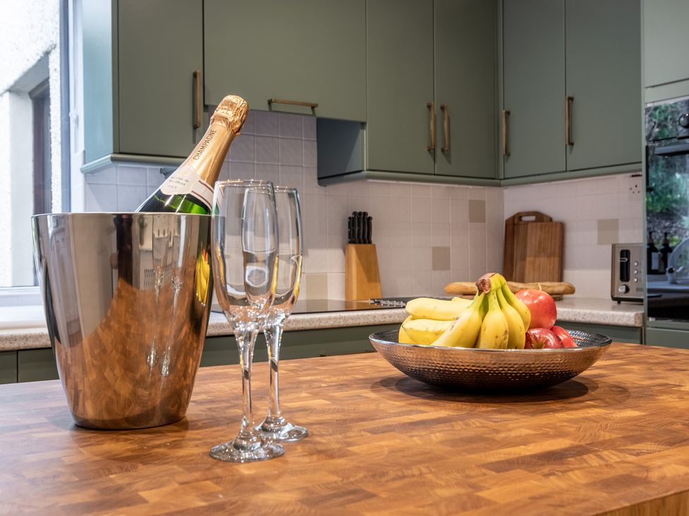 A kitchen with a champagne bottle and fruit bowl at Marina View in Bowness-On-Windermere