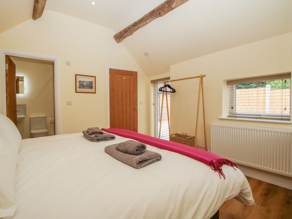 A bedroom with a bed towels and window at The Old Piggery in Shifnal