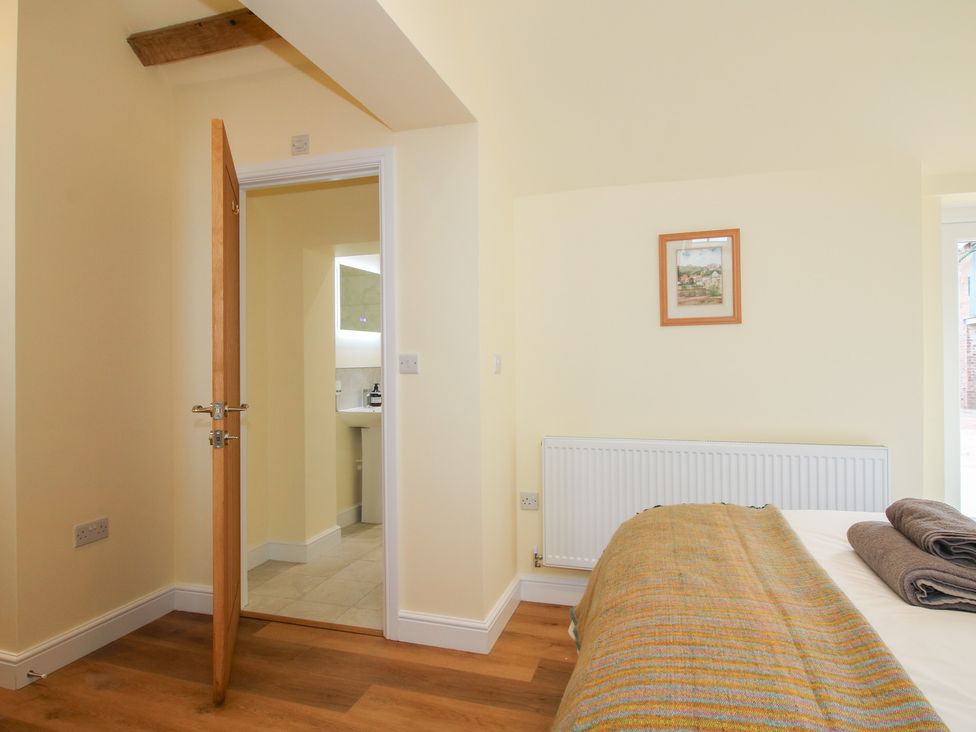 A bedroom with a bed and door leading to a bathroom at Old Piggery in Shifnal