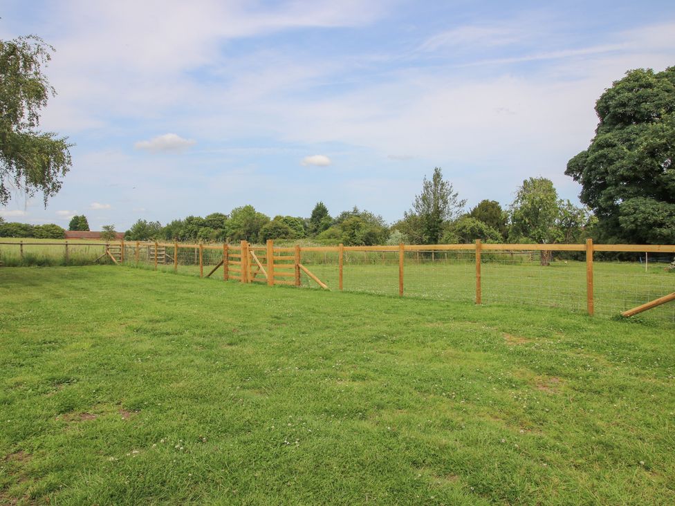 A fenced area with grass and trees at The Old Piggery in Shifnal