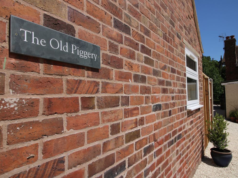 A brick wall with a nameplate on The Old Piggery in Ironbridge
