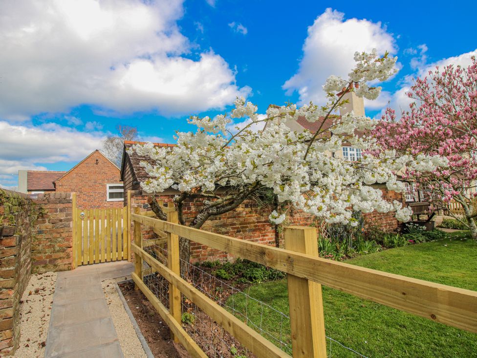 A garden with a wooden fence and flowering trees at The Old Piggery in Ironbridge