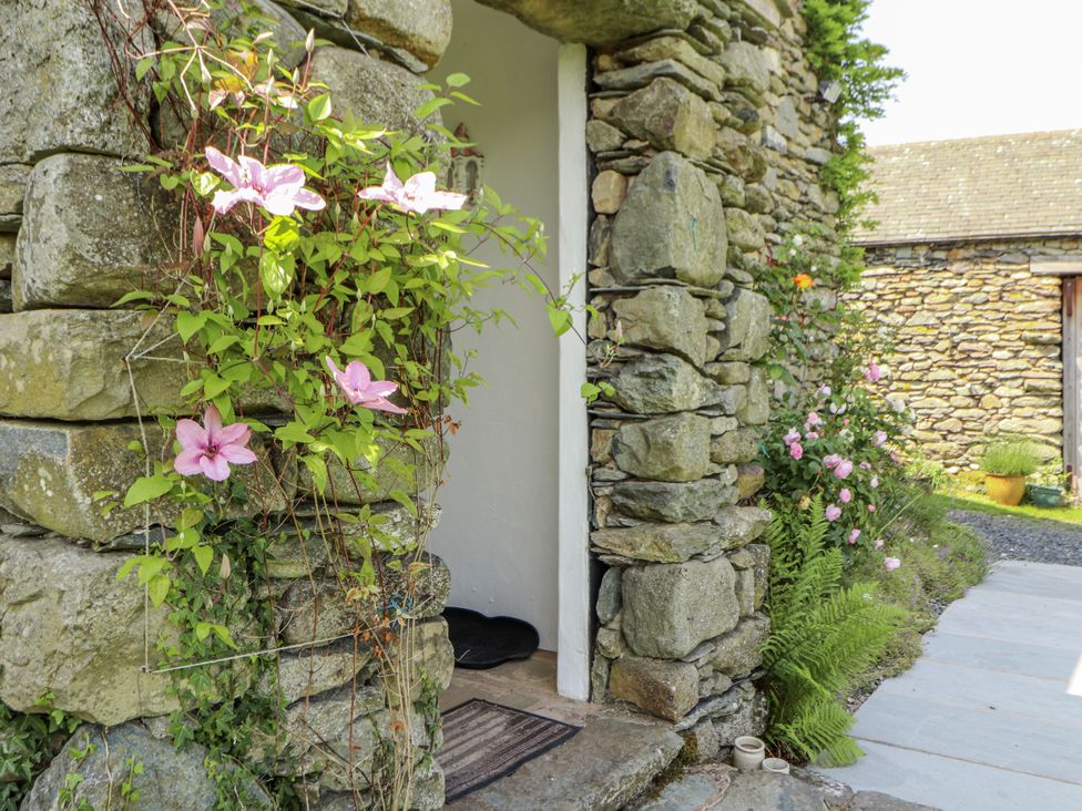 A garden with climbing plants and a stone wall at High Wood Foot in Bampton, Cumbria