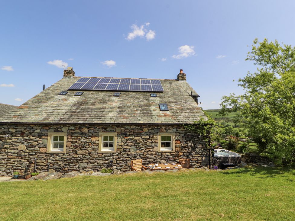 A stone house with solar panels and a garden at High Wood Foot in Bampton, Cumbria
