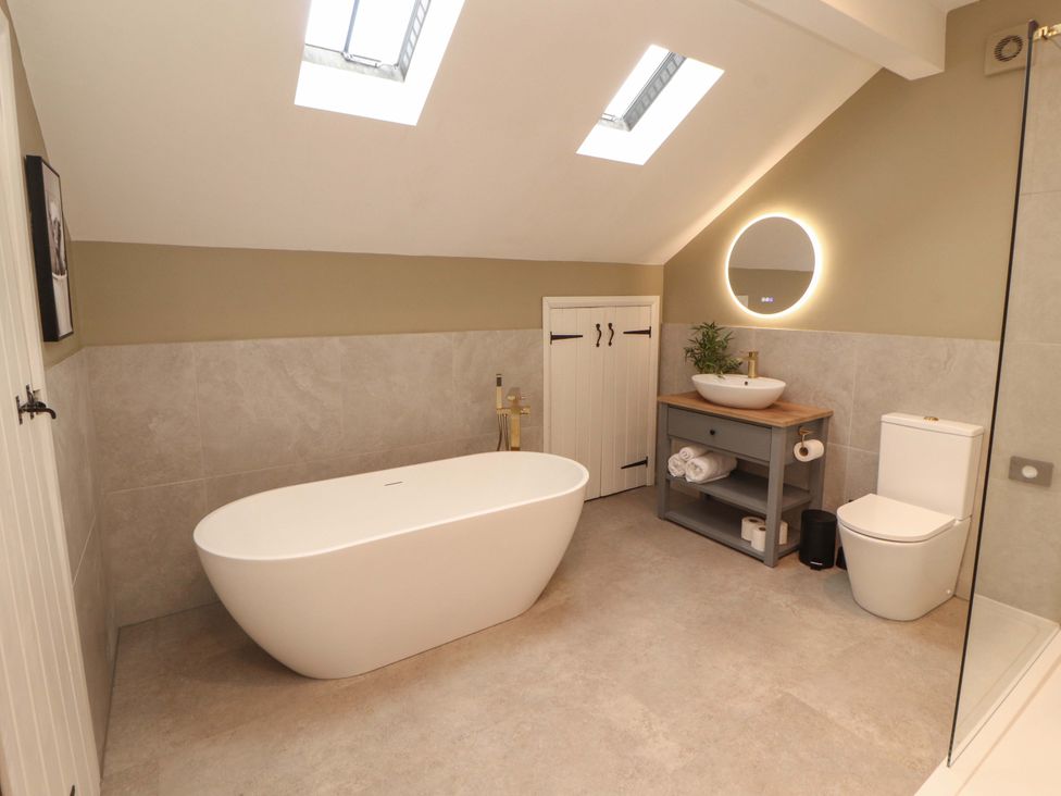 A bathroom with a bathtub, toilet and sink at High Wood Foot in Bampton, Cumbria