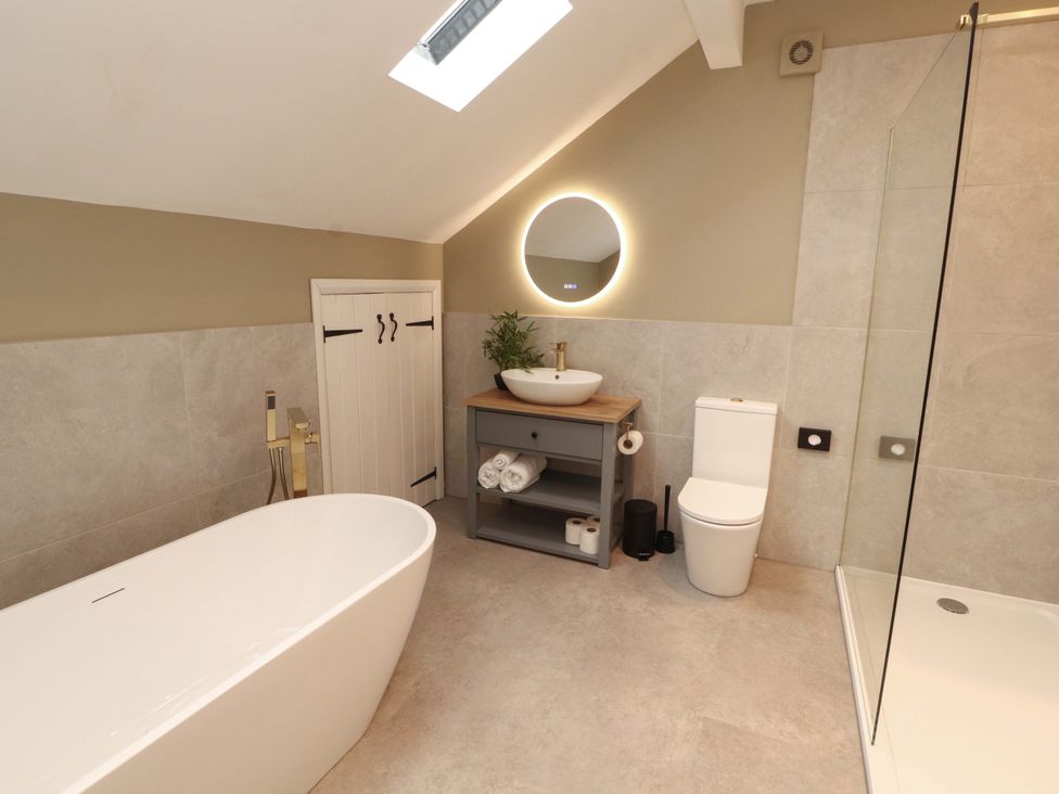 A bathroom with a bathtub, sink, and shower at High Wood Foot, Bampton, Cumbria