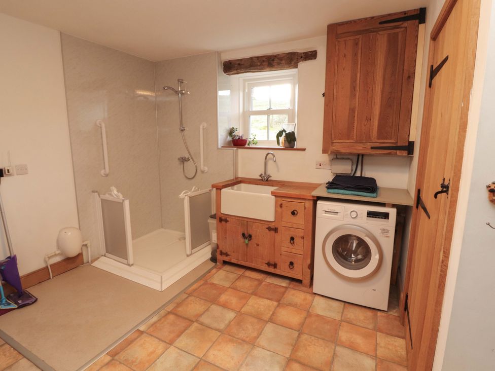 A bathroom with a shower, sink, and washing machine at High Wood Foot, Bampton, Cumbria
