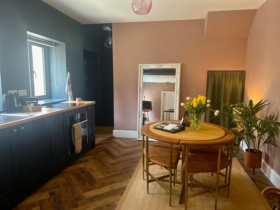 A kitchen with a table and flowers at The Balmoral Coach House in Morecambe