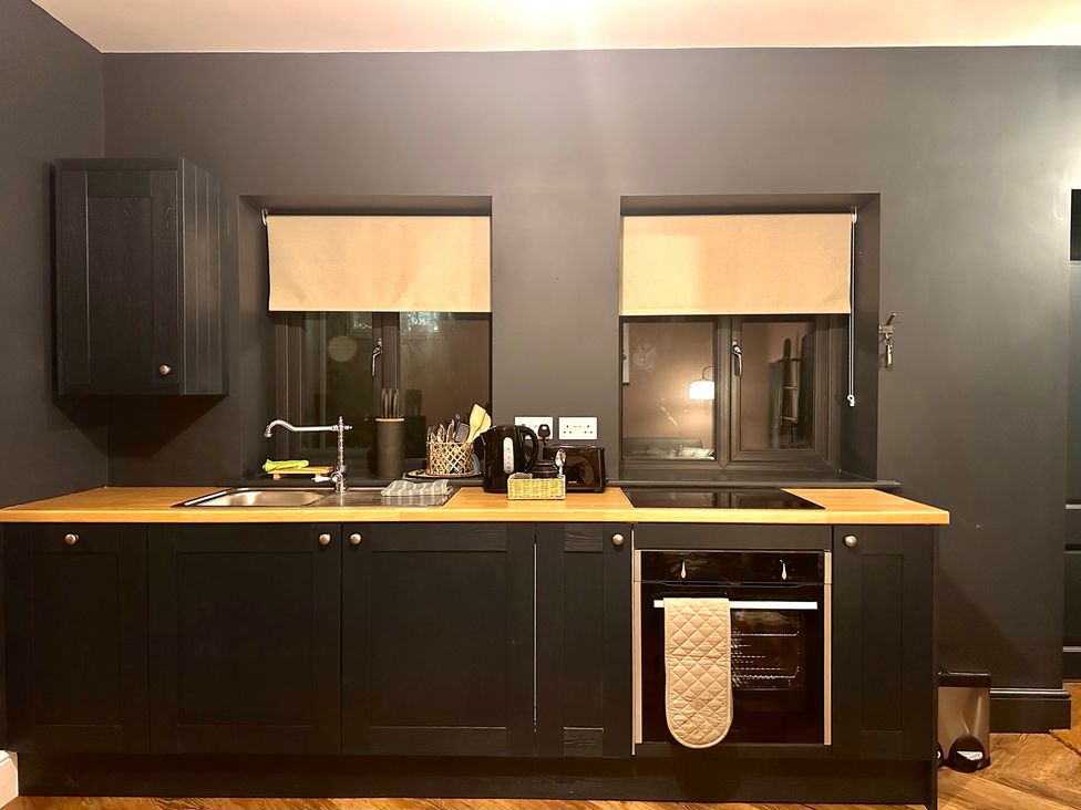 A kitchen with cabinets, sink, window, and oven at The Balmoral Coach House in Morecambe