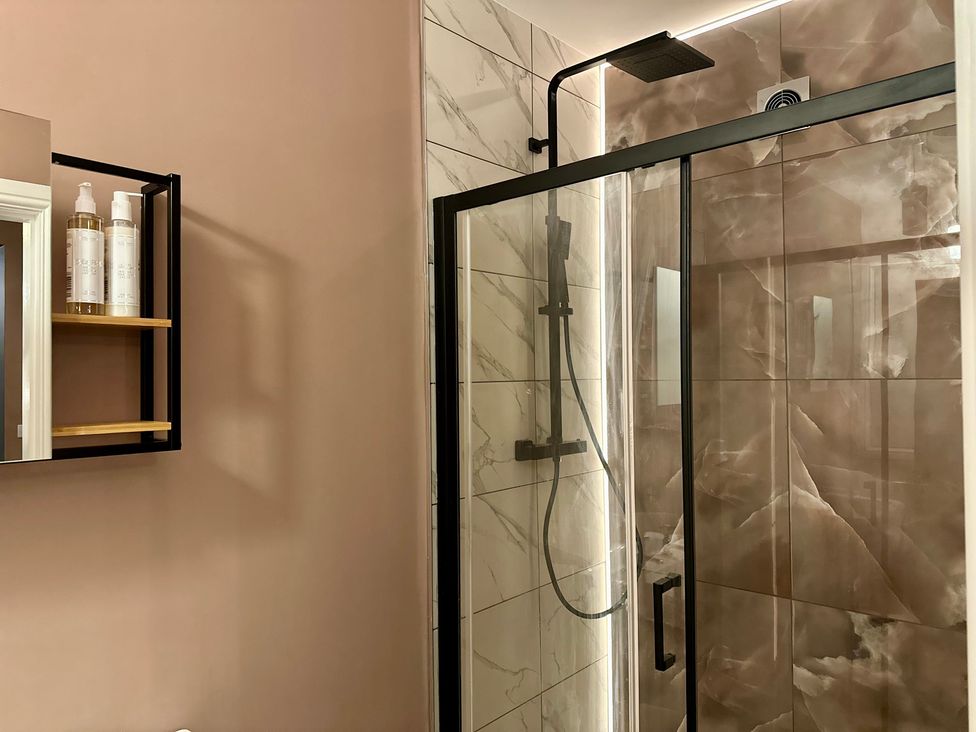 A bathroom with a shower and shelf at The Balmoral Coach House in Morecambe