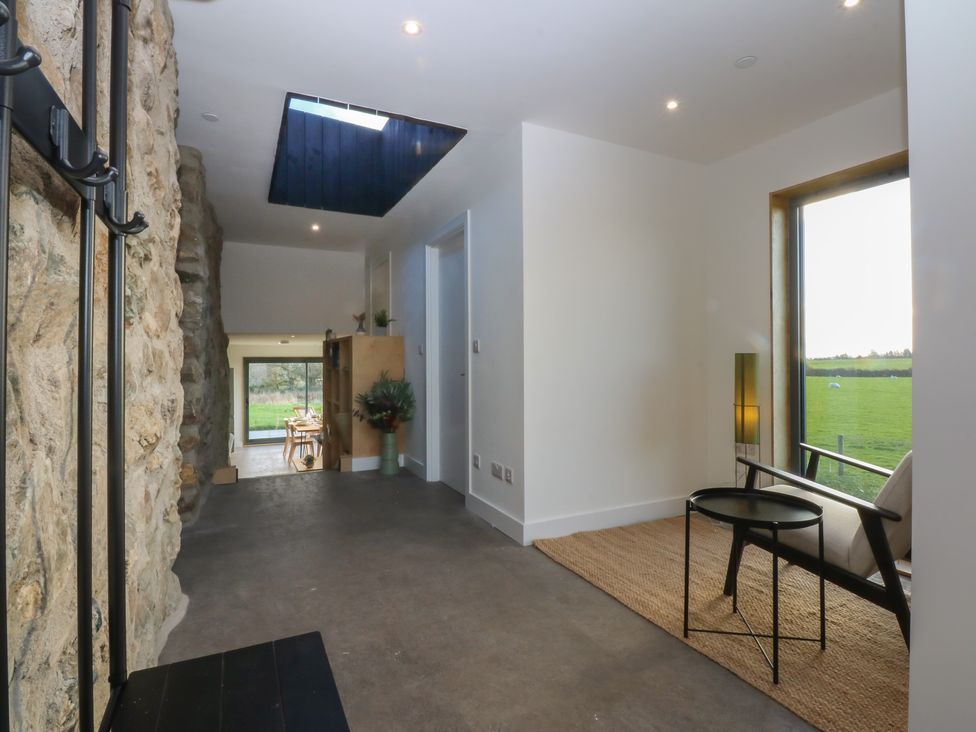 An entrance hall with a stone wall and a skylight at Tithe Barn Lodge Capel Mawr near Malltraeth