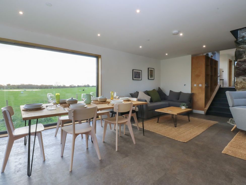 A dining room with a table and chairs at Tithe Barn Lodge Capel Mawr near Malltraeth