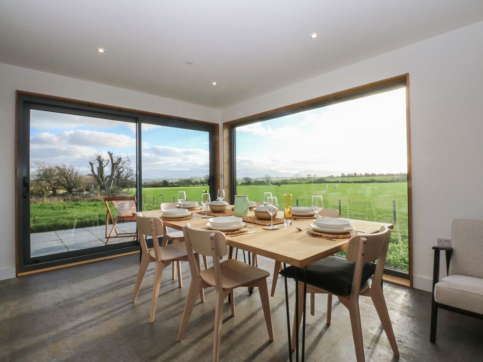 A dining room with a table set for a meal at Tithe Barn Lodge Capel Mawr near Malltraeth
