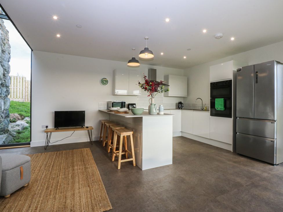 A kitchen with modern appliances and seating at Tithe Barn Lodge near Capel Mawr
