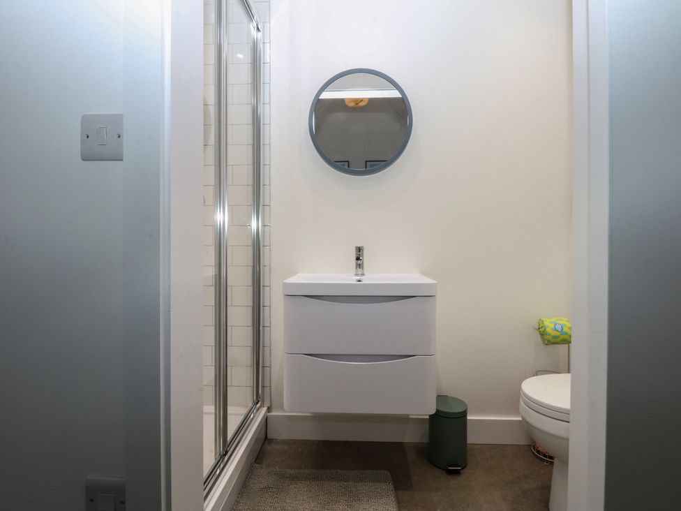 A bathroom with a shower, sink, and toilet at Tithe Barn Lodge Capel Mawr near Malltraeth