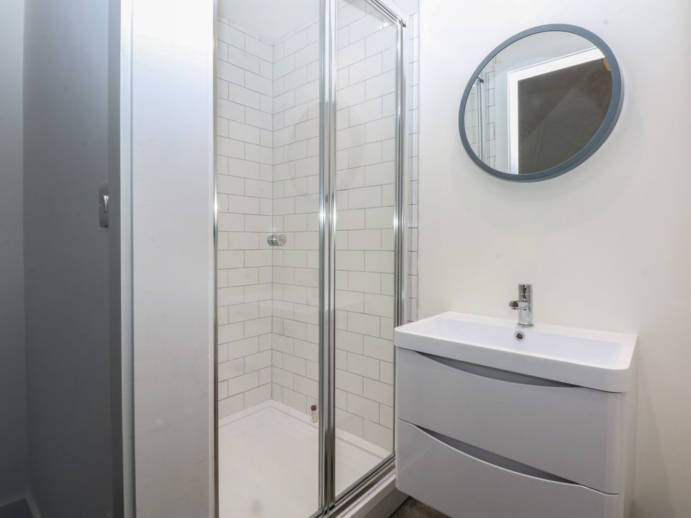 A bathroom with a shower and sink at Tithe Barn Lodge Capel Mawr near Malltraeth
