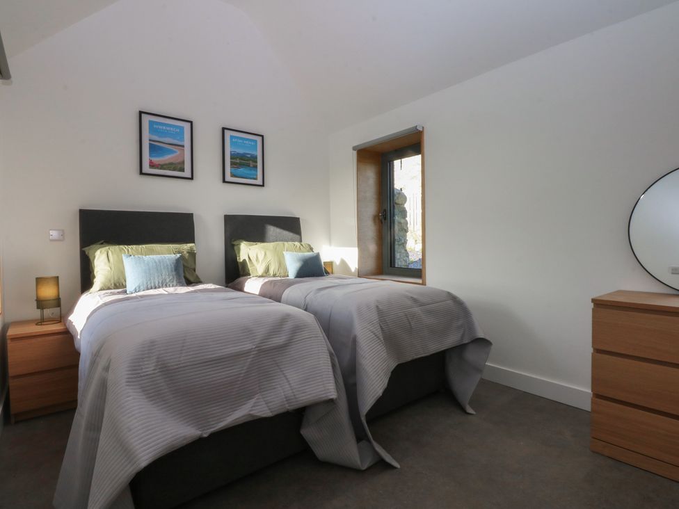 A bedroom with twin beds and a window at Tithe Barn Lodge in Capel Mawr near Malltraeth