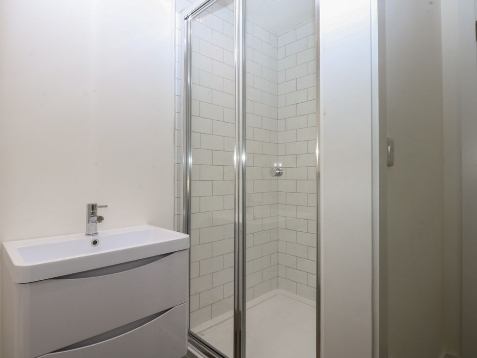 A bathroom with a shower and sink at Tithe Barn Lodge near Malltraeth