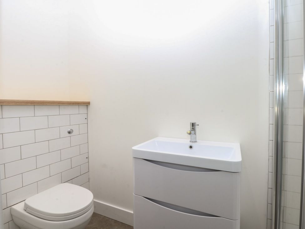A bathroom with a sink, toilet, and shower at Tithe Barn Lodge Capel Mawr near Malltraeth