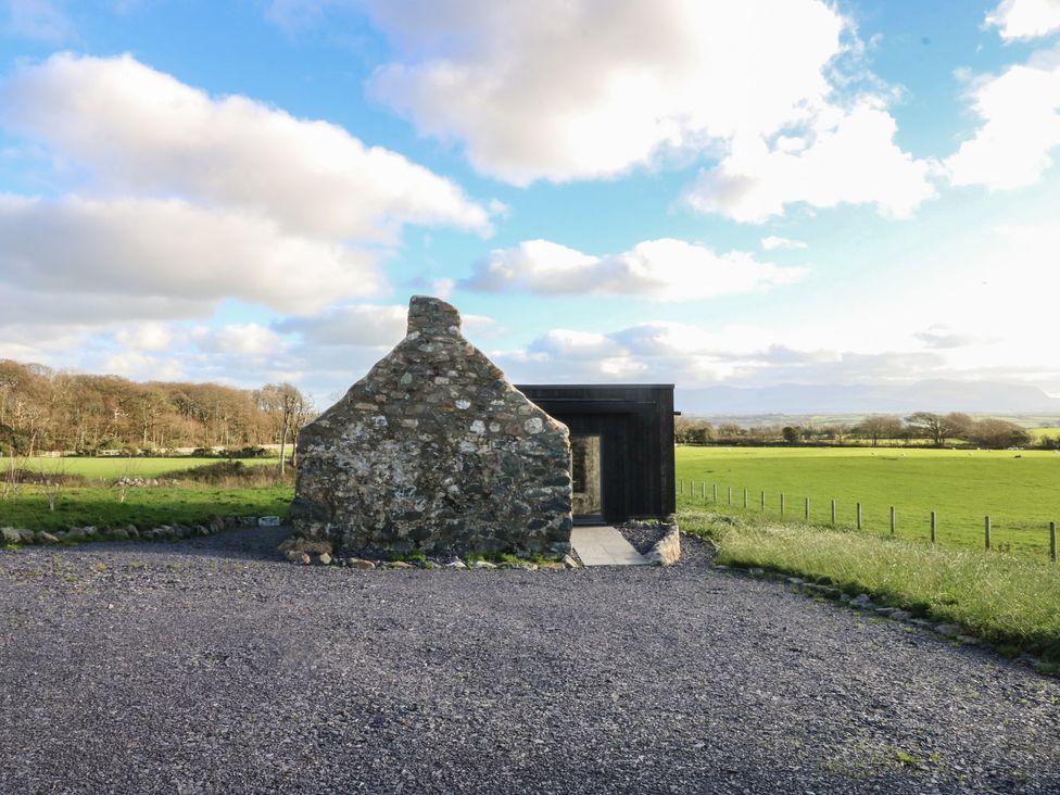 A stone and modern building with a gravel path at Tithe Barn Lodge Capel Mawr near Malltraeth