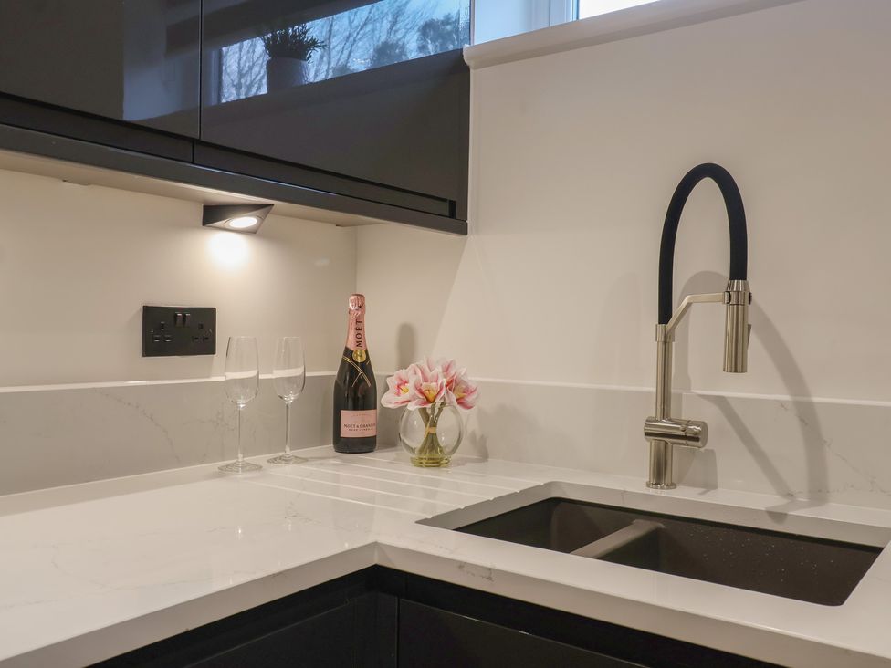 A kitchen countertop with a sink and champagne bottle at Oak lodge Westonzoyland nr. Bridgwater