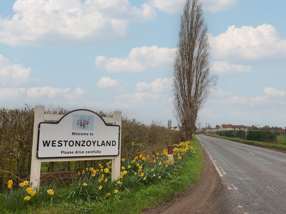 A welcome sign to Westonzoyland along a road with flowers at Westonzoyland nr. Bridgwater
