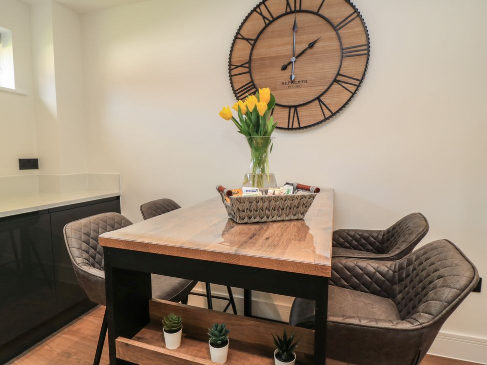 A dining room with a table, chairs, flowers, and a clock at Oak Lodge Westonzoyland nr. Bridgwater