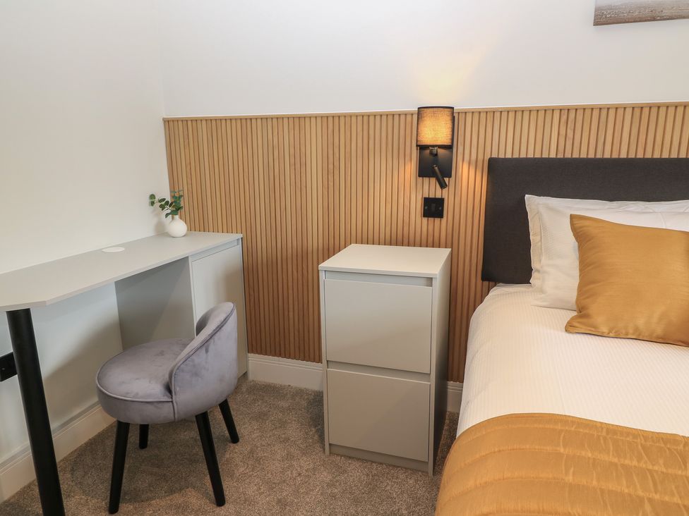 A bedroom with a desk, chair, bedside table, and lamp at Oak Lodge in Westonzoyland nr. Bridgwater