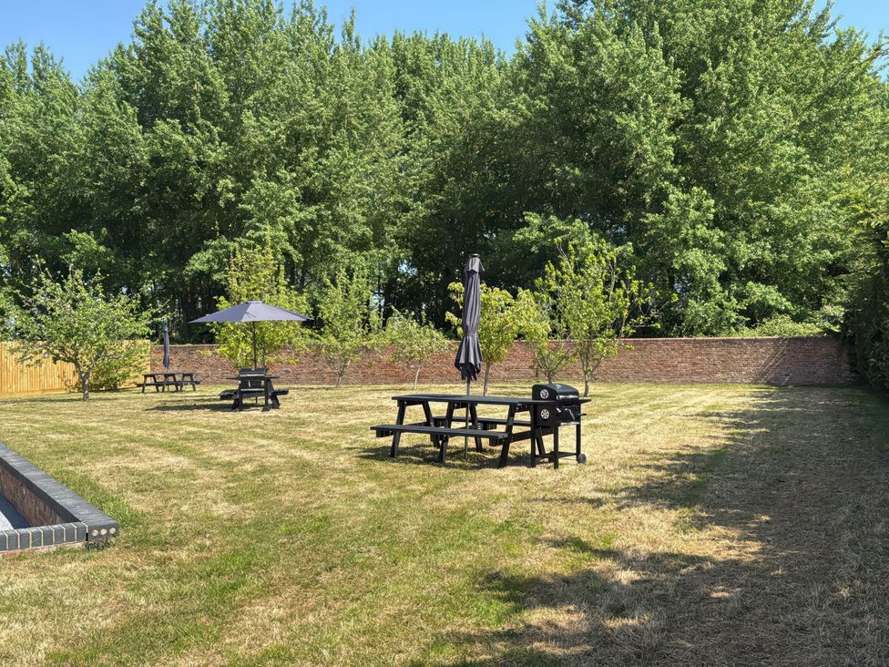 A garden with picnic tables and umbrellas at Pine Lodge in Bridgwater