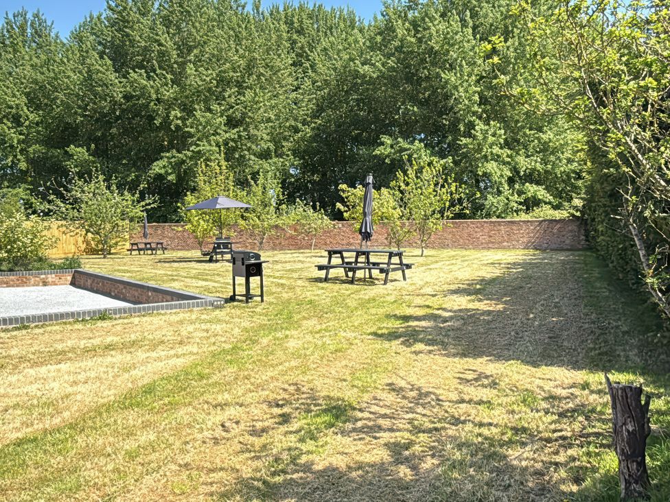 A garden with picnic tables and trees at Pine Lodge in Bridgwater
