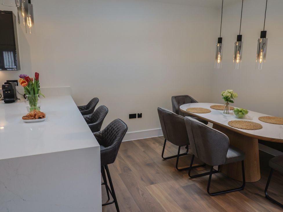 A kitchen with a dining table and bar stools at Maple Lodge Westonzoyland nr. Bridgwater