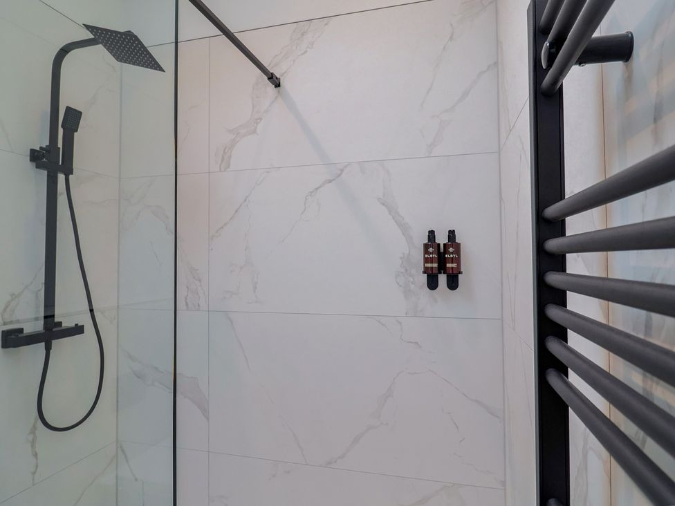 A shower with a black showerhead and wall mounted bottles at Maple Lodge Westonzoyland nr. Bridgwater