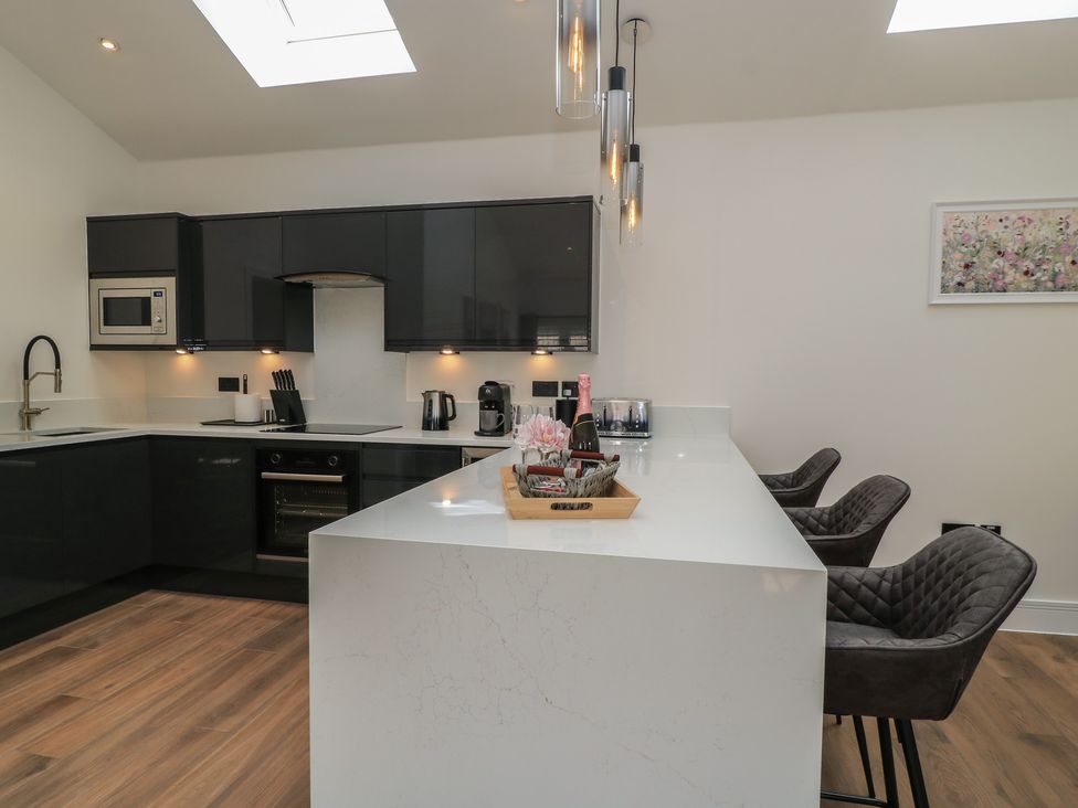 A kitchen with a sink and bar stools at Maple Lodge Westonzoyland near Bridgwater