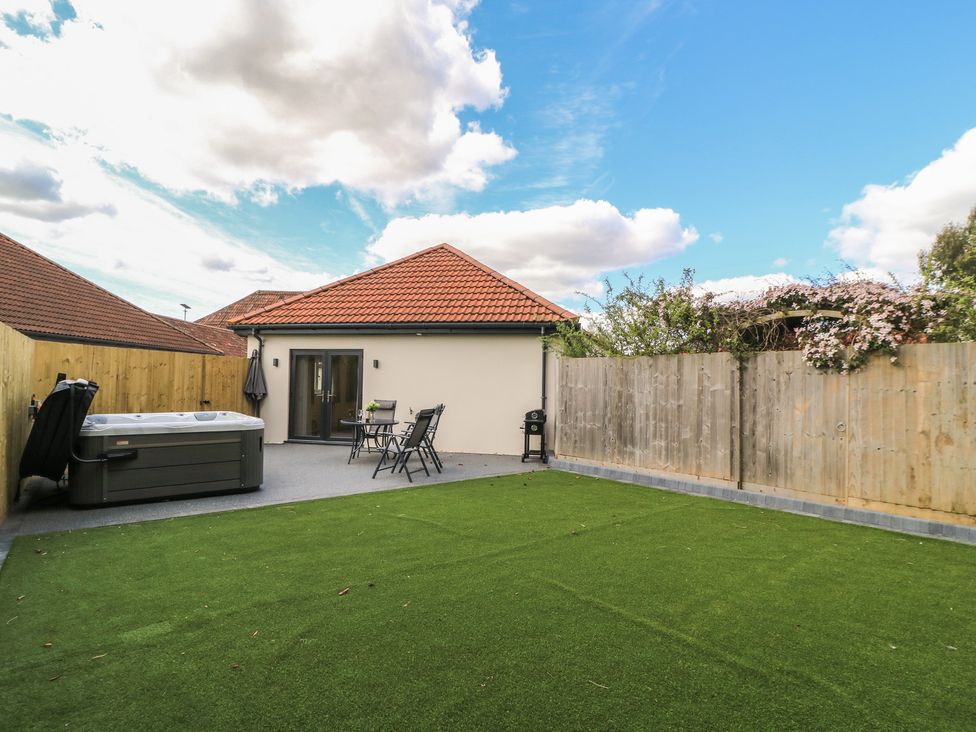 A garden with a hot tub and seating at Maple Lodge in Westonzoyland near Bridgwater