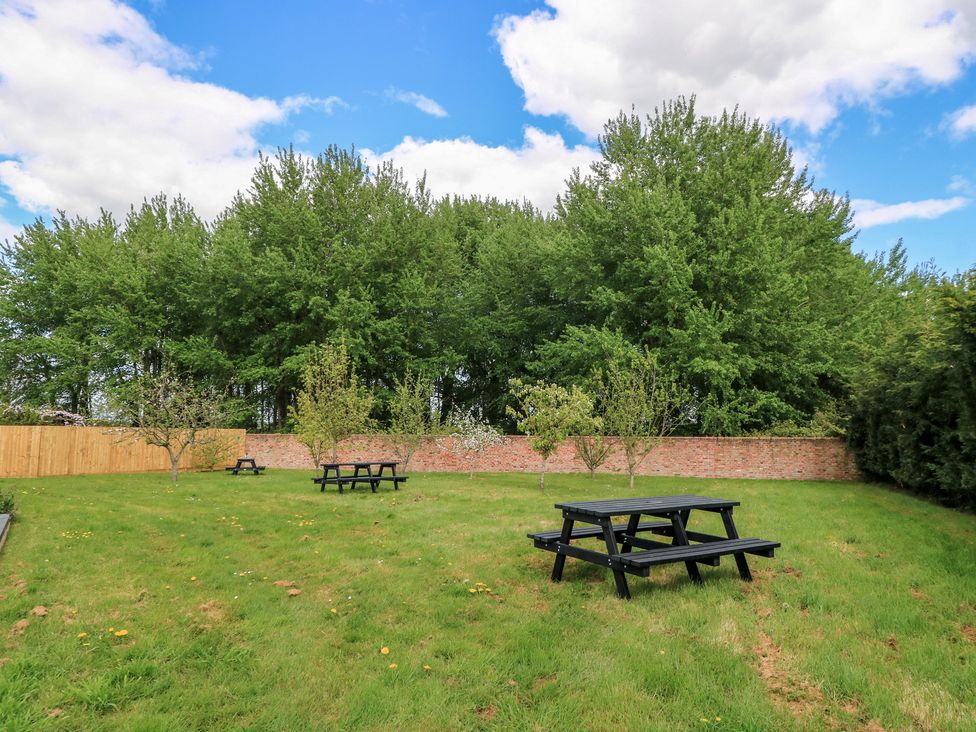 A garden with trees and picnic tables at Maple Lodge Westonzoyland near Bridgwater