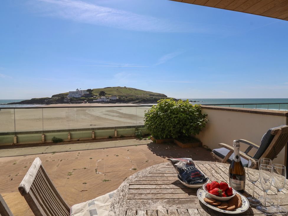 An outdoor patio with a table and chairs overlooking the sea at 6 Burgh Island in Bigbury-On-Sea