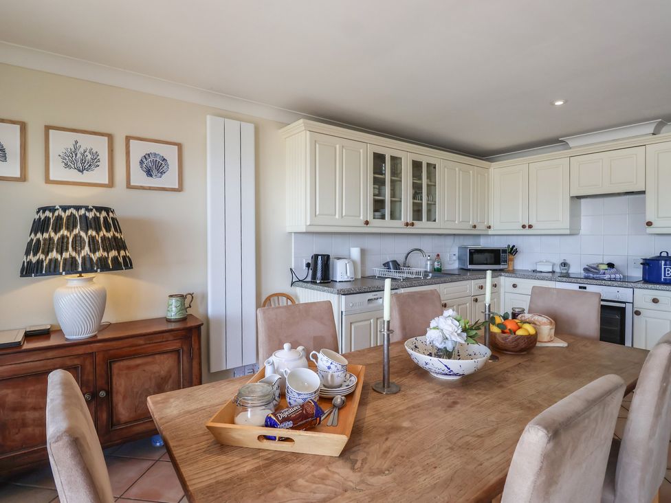 A kitchen with a dining table and fruits at 6 Burgh Island in Bigbury-On-Sea