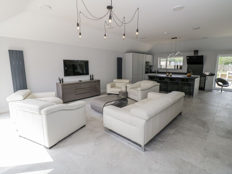 A living room with a television and kitchen island at Chillon South Littleton near Honeybourne