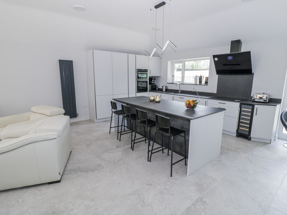 A kitchen with an island and stools at Chillon in South Littleton near Honeybourne
