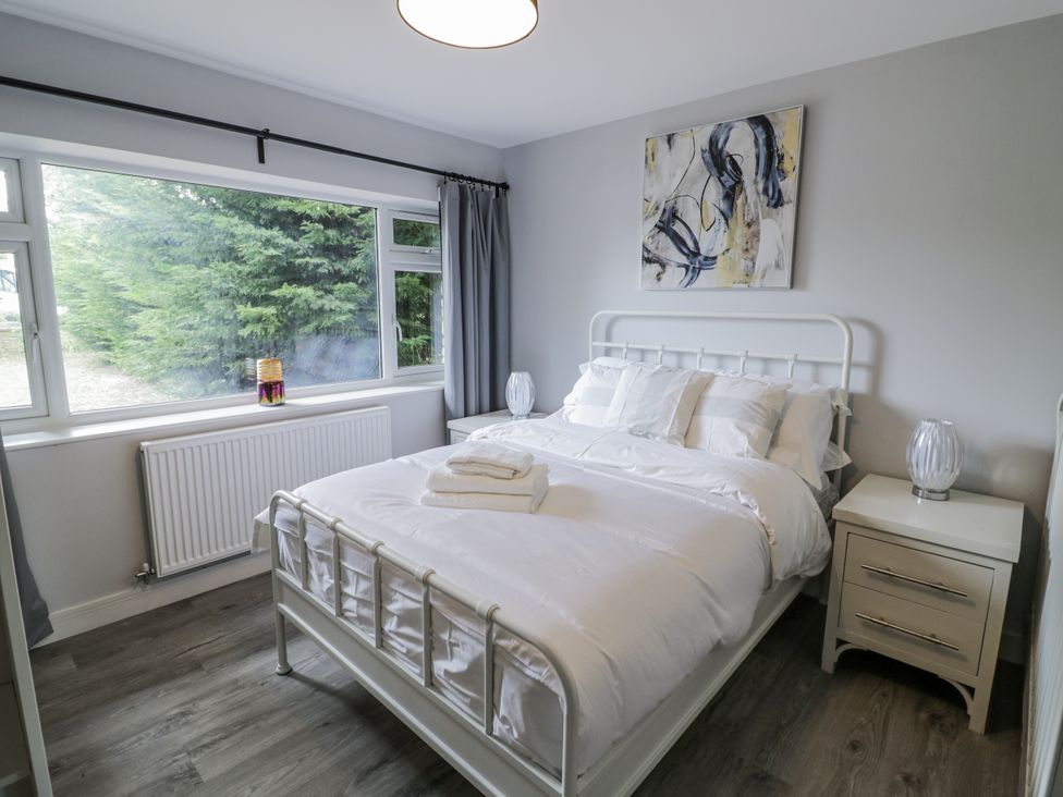 A bedroom with a bed, bedside table, and window at Chillon in South Littleton near Honeybourne