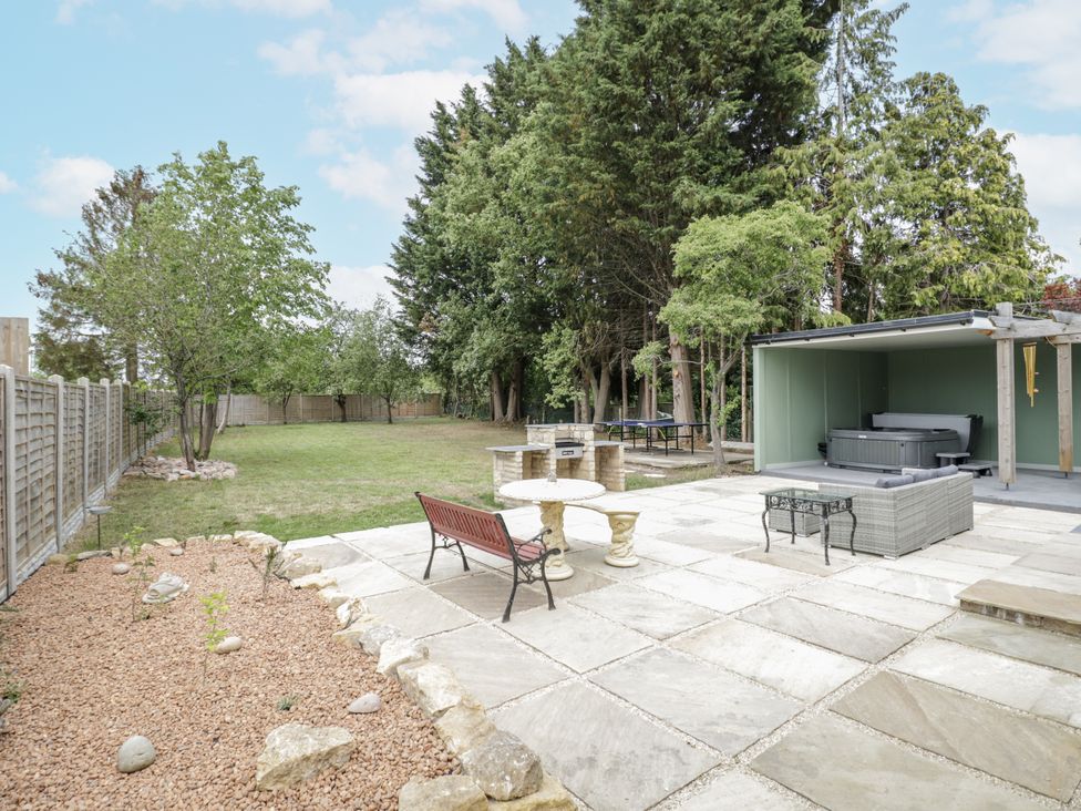 A garden with a patio area and a hot tub at Chillon South Littleton near Honeybourne