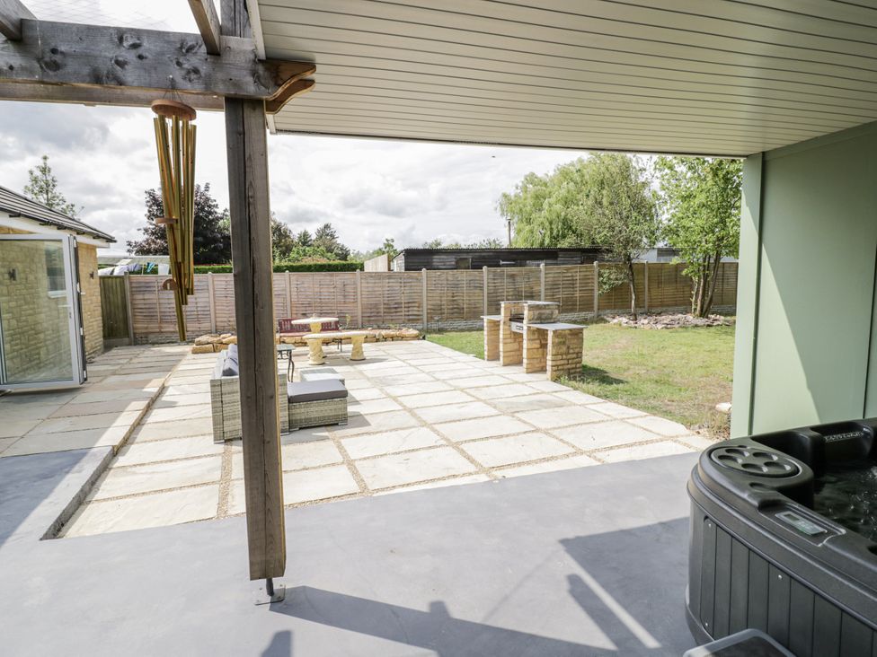 An outdoor patio with seating and hot tub at Chillon South Littleton near Honeybourne