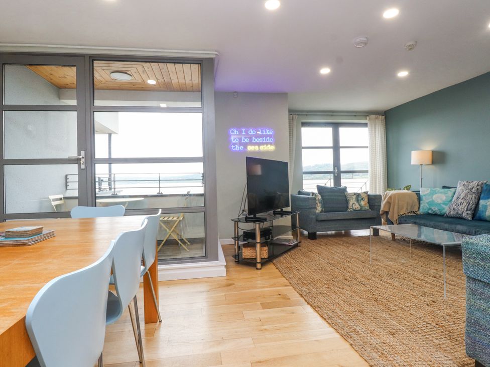 A living room with a dining area and balcony at 2 The Quay Pentraeth
