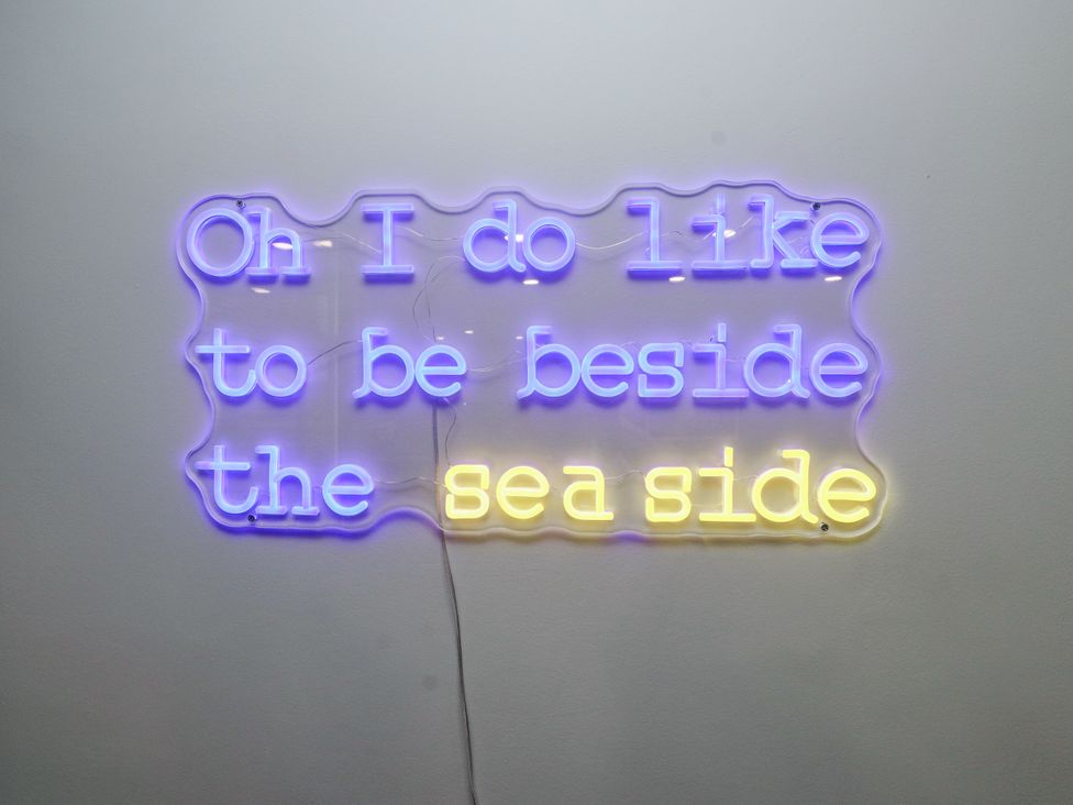 A neon sign that says Oh I do like to be beside the sea side at 2 The Quay Pentraeth