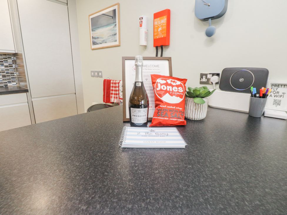 A kitchen counter with a bottle of prosecco and snacks at 2 The Quay Pentraeth
